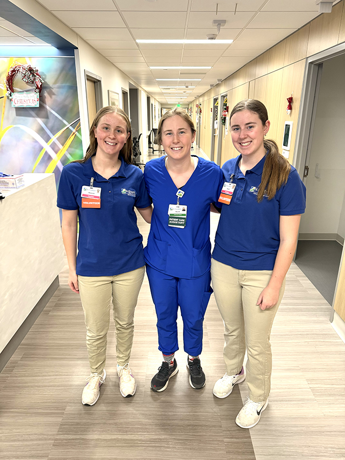 Two volunteers pose with a clinician in the hospital